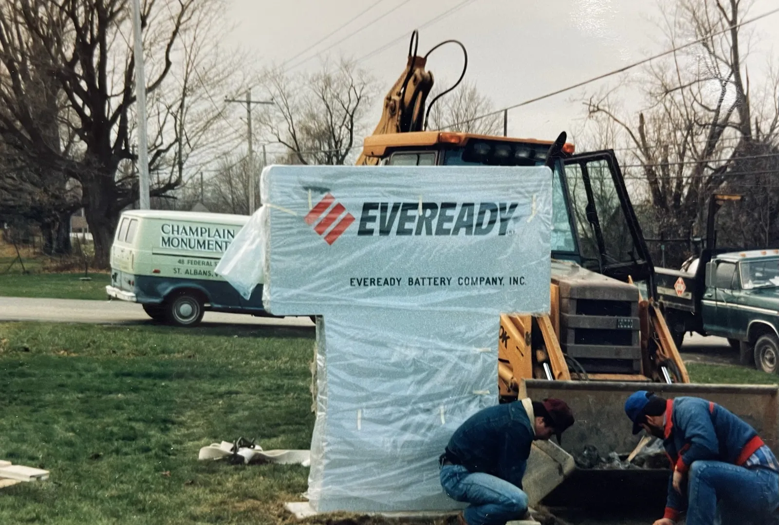 Setting a wrapped Eveready Battery Company commemorative monument with the Champlain Monuments van and a backhoe on site