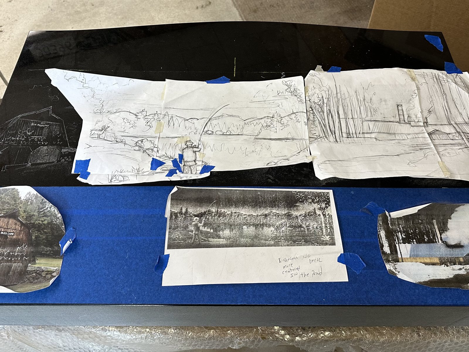 Reference photos taped to a polished black granite slab with pencil sketches laid over the surface
