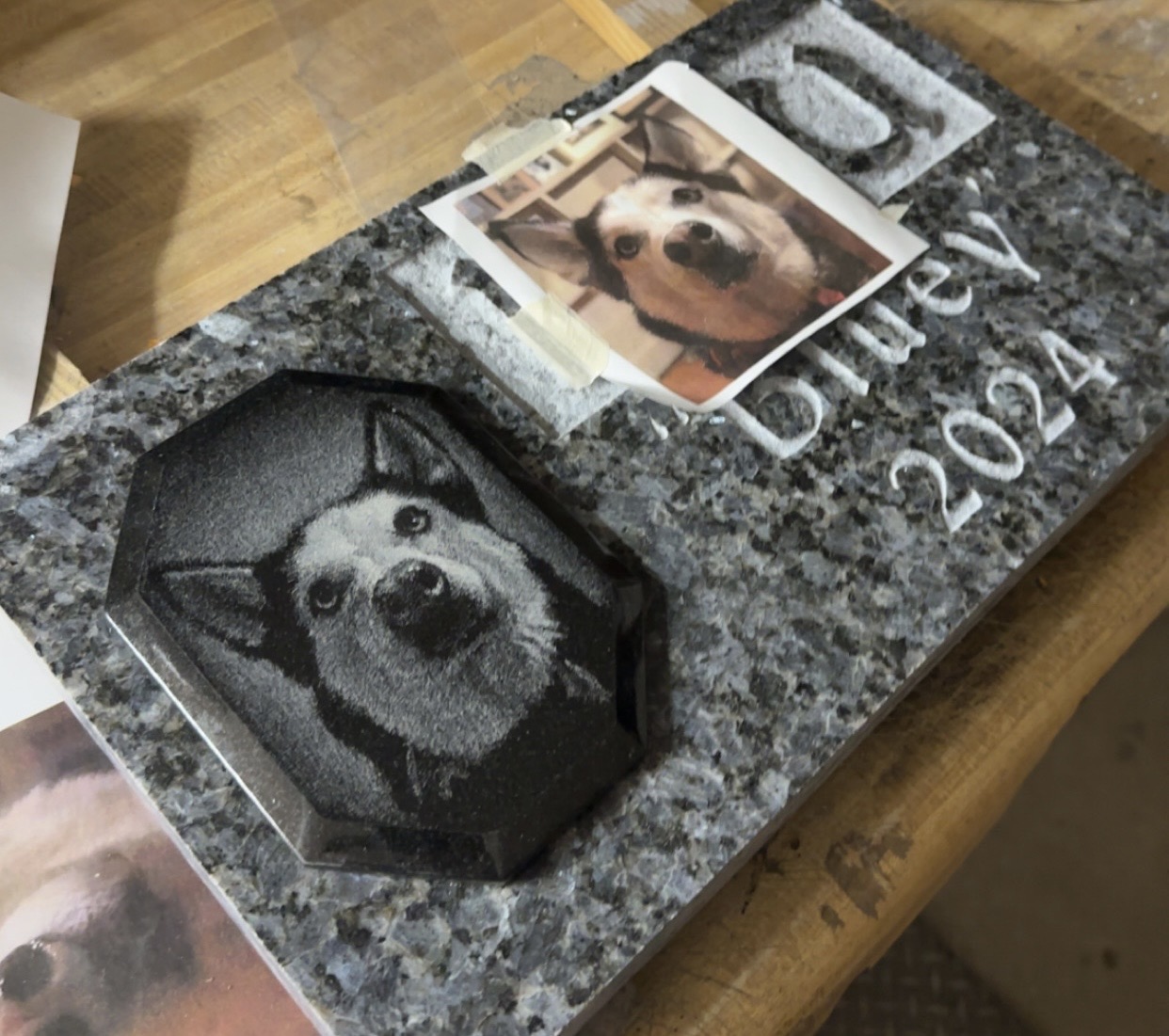 Hand-etched pet portrait on a polished black granite marker shown next to the reference photograph for comparison