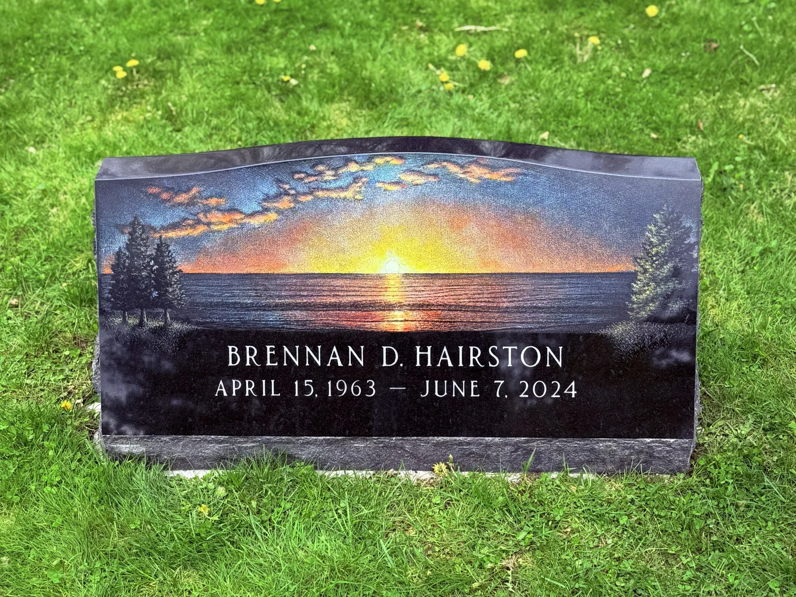 Hand-etched lake sunset scene on a polished black granite slant memorial — Brennan D. Hairston