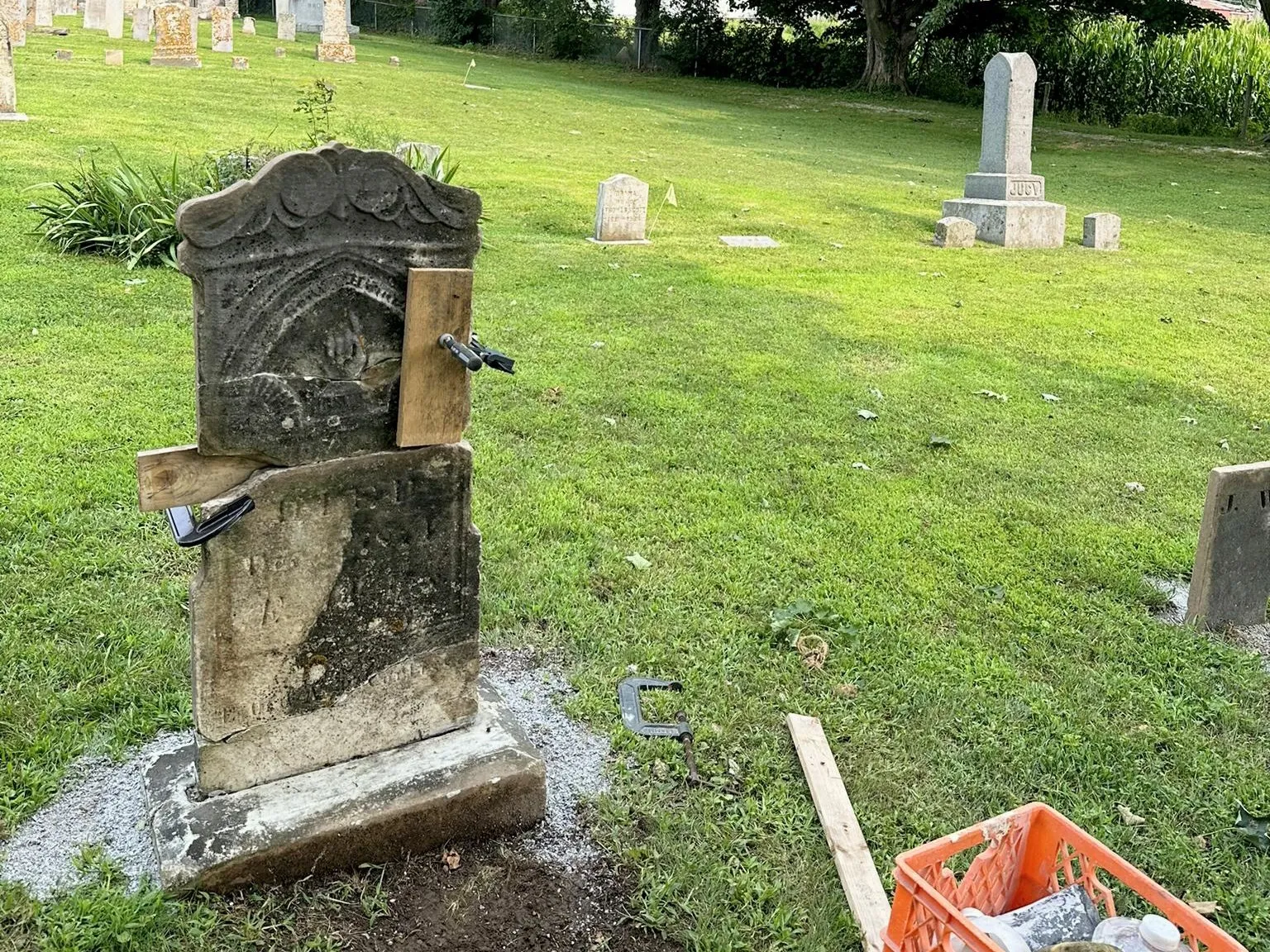 An older marble tablet held with clamps mid-repair, work materials staged at the stone