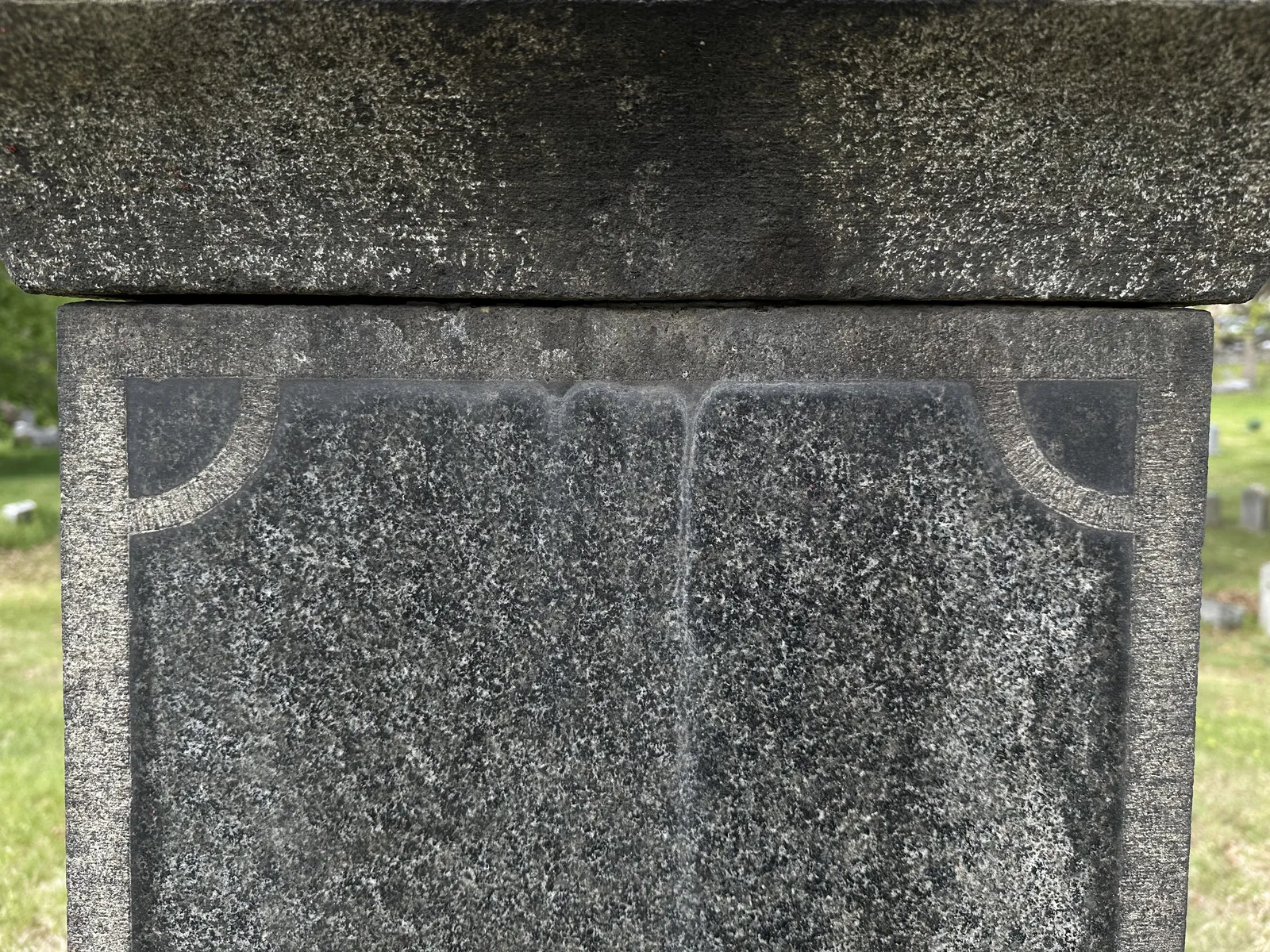 A polished dark granite panel showing pale vertical calcium efflorescence from the upper joint and patchy dark staining bonded into the polish