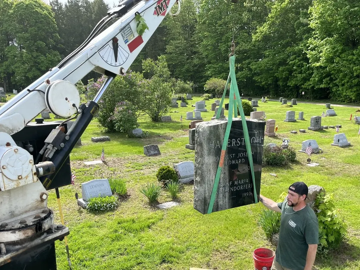 Crew using a crane to set a custom granite monument in a Vermont cemetery