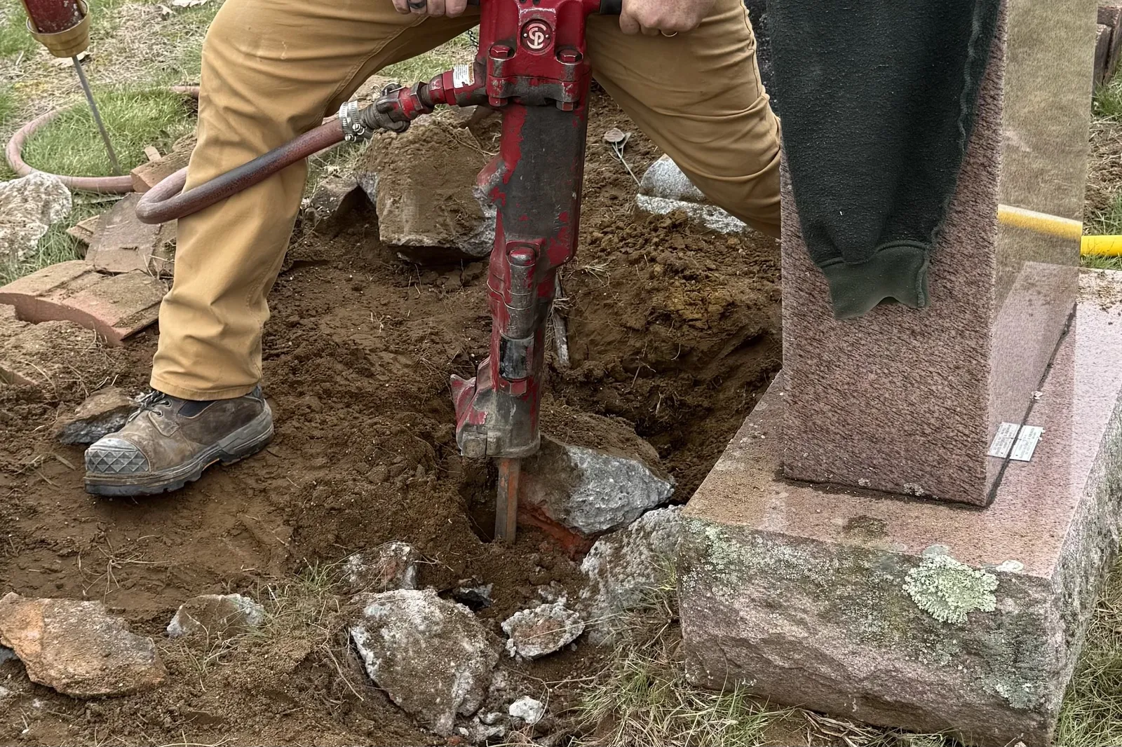 Jackhammer breaking up an old monument foundation during a reset