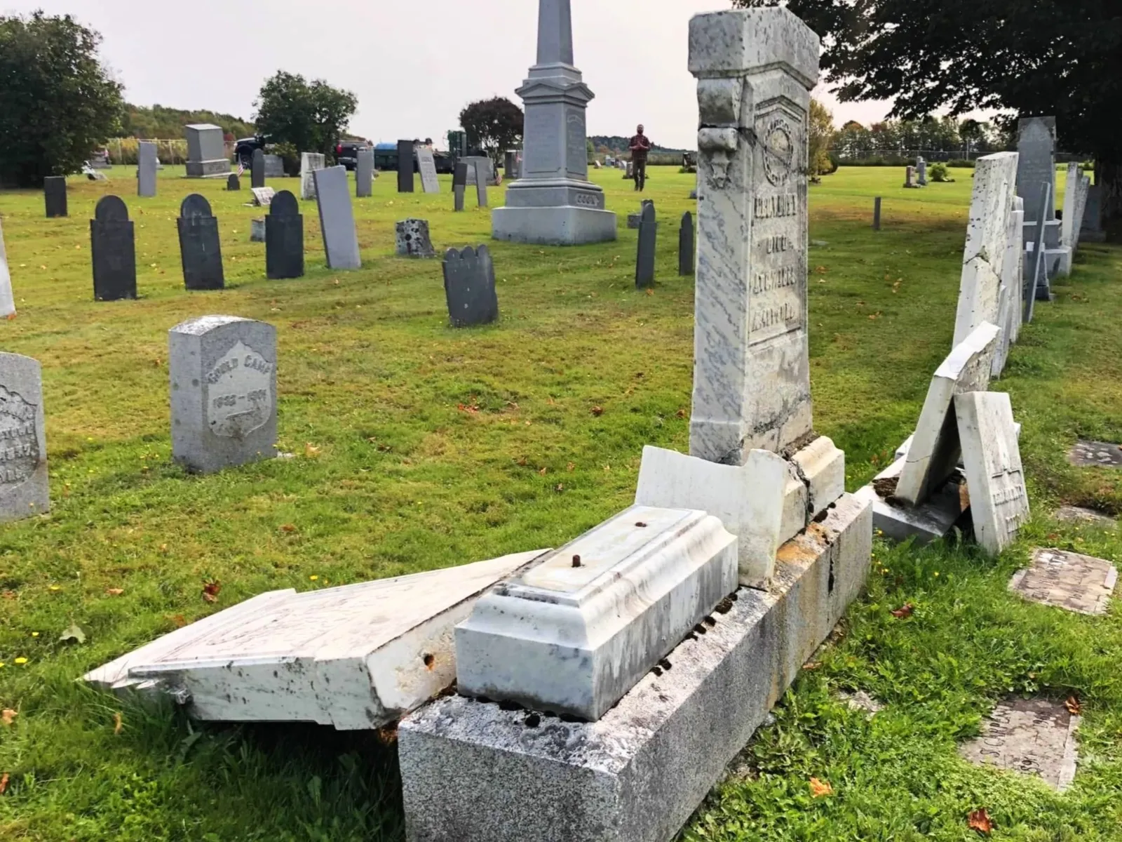 Tablet memorial fallen from its base, broken into sections on the ground